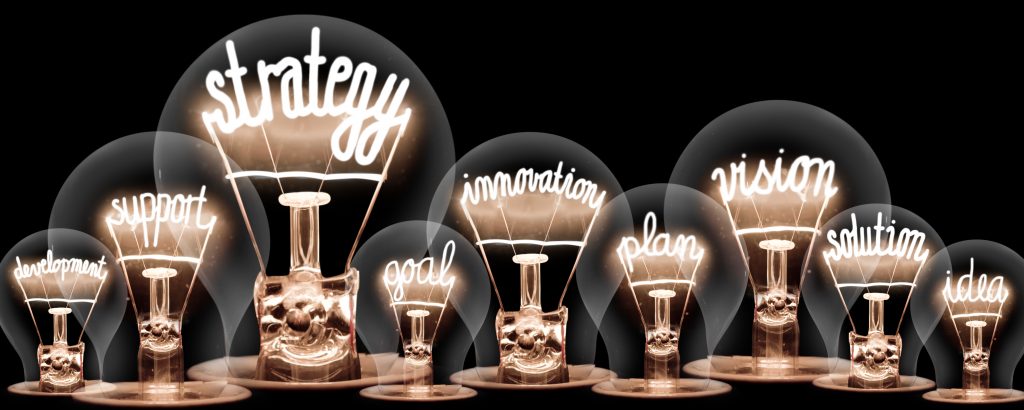 Photo of light bulbs group with shining fibers in a shape of STRATEGY concept related words isolated on black background